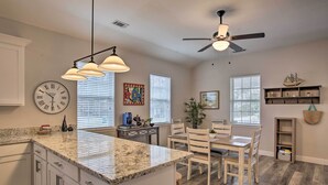 A spacious kitchen with a large island, white cabinetry, and a clock on the wall.
