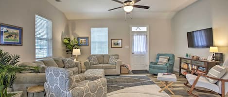 A spacious living room with a ceiling fan, a sofa set, a rocking chair, and a television.