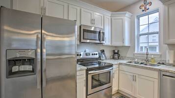 A modern kitchen with stainless steel appliances, white cabinetry, and a window with a view.