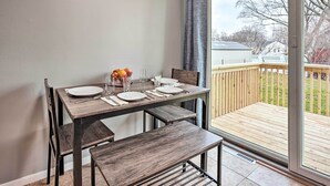 Ein Essbereich mit einem für vier Personen gedeckten Tisch, einer Bank und einer Glastür zum Balkon.