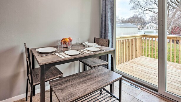 A dining area with a table set for four, a bench, and a sliding glass door leading to a deck. - Homey Duplex - 10 Mi to Downtown Grand Rapids! (Jenison)