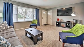 A living room with a sofa, a coffee table, a patterned armchair, and a fireplace. - Homey Duplex - 10 Mi to Downtown Grand Rapids! (Jenison)