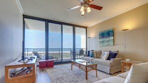A spacious living area with a balcony, a sofa, a coffee table, and a television.