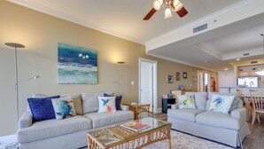A living room with two sofas, a glass coffee table, and a painting on the wall.