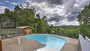 A swimming pool with a wooden deck and lounge chairs, surrounded by trees and a cloudy sky. - Branson Condo w/ Views: 2 Mi to Silver Dollar City (Branson West)