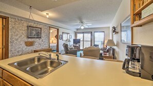 A kitchen with a double sink, a coffee maker, and a dining area with a chair and a table. - Branson Condo w/ Views: 2 Mi to Silver Dollar City (Branson West)