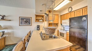 A kitchen with wooden cabinets, a stainless steel refrigerator, a microwave, and a hanging basket. - Branson Condo w/ Views: 2 Mi to Silver Dollar City (Branson West)