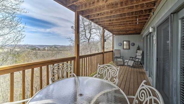 A covered outdoor deck with a round table and white chairs, overlooking a scenic landscape. - Branson Condo w/ Views: 2 Mi to Silver Dollar City (Branson West)