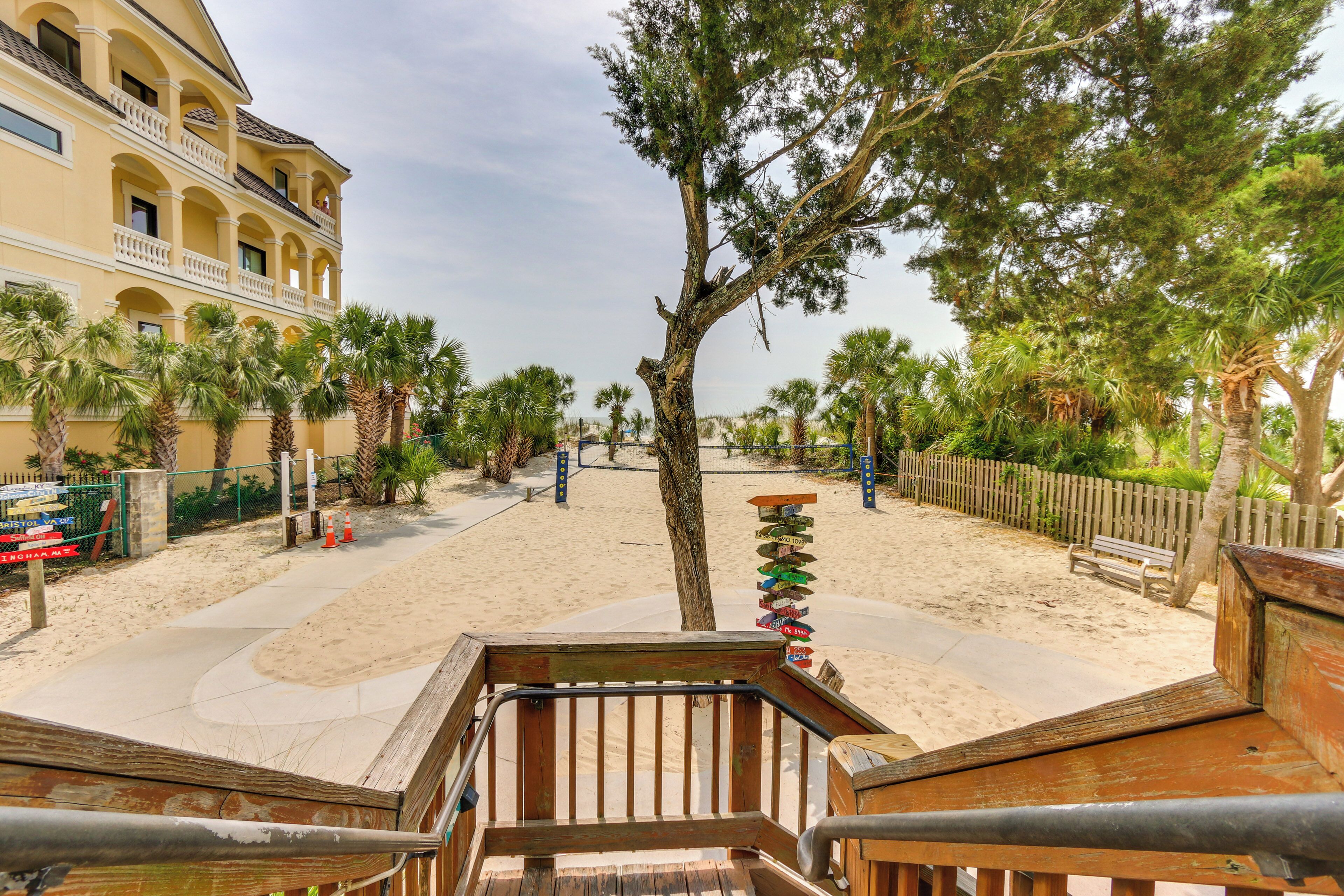 Une propriété située en bord de mer, dotée d’une terrasse en bois, de palmiers et d’une plage de sable.