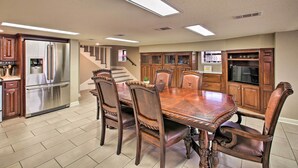 Una cocina amplia con una gran mesa de comedor, armarios de madera y un refrigerador de acero inoxidable.