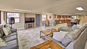 Amplia sala de estar con televisor grande, asientos cómodos, zona de cocina y comedor.