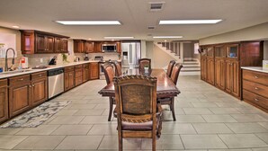 Una cocina amplia con armarios de madera, una isla central y un comedor con sillas.