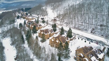 Un complejo turístico nevado con varias construcciones, un telesilla y una carretera.