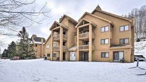 A multi-story wooden building with balconies, a snow-covered ground, and a few trees in the background. - Golf & Adventure! Condo 2 Mi to Dtwn Ellicottville (Great Valley)