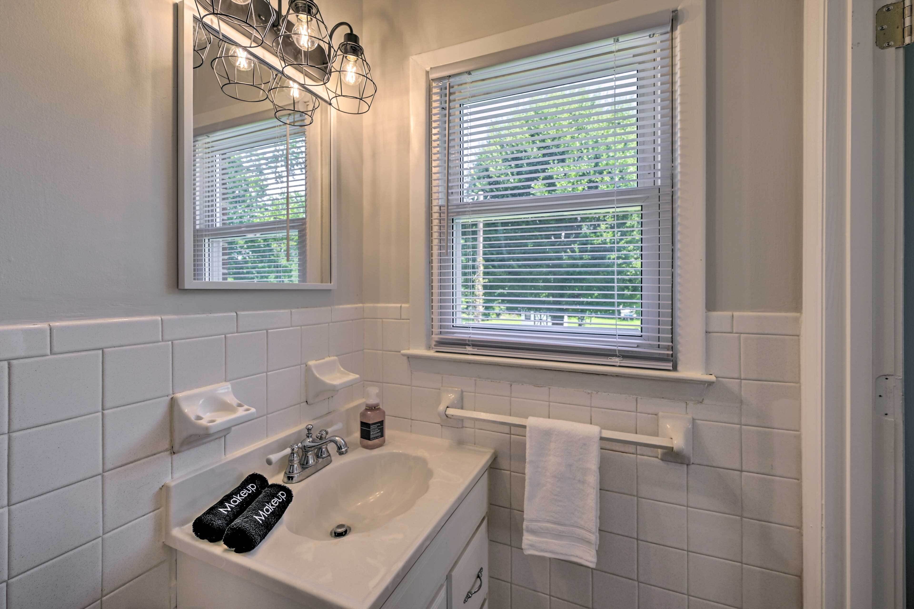 A bathroom with a white sink, two towels, a soap dispenser, and a mirror above the sink.