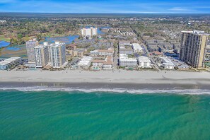 An aerial view of a coastal area with high-rise buildings, a beach, and a marina.