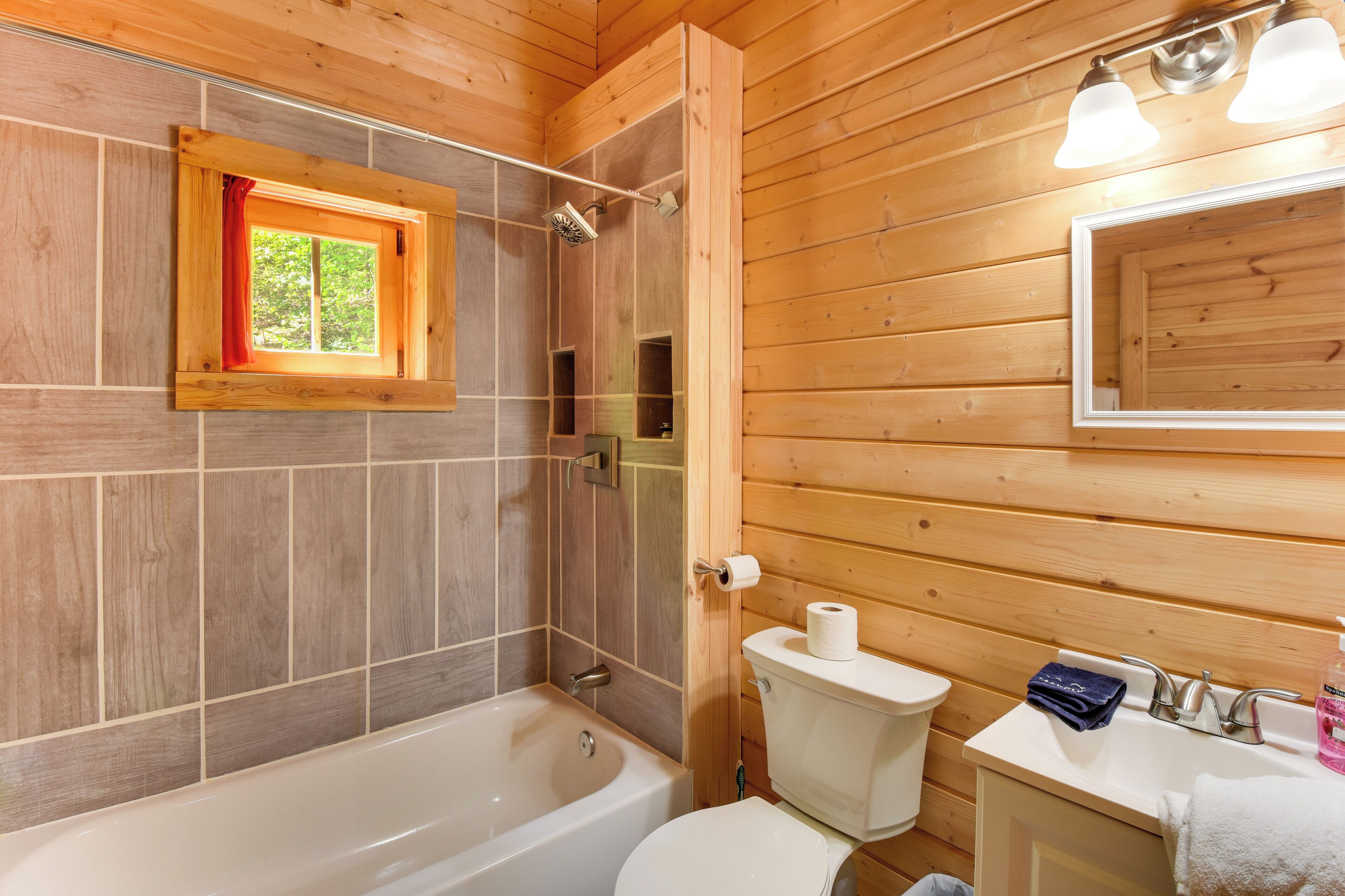 Bagno di una baita in legno con vasca, water e lavandino.
