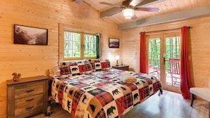Een houten slaapkamer met een bed, nachtkastje en ramen.