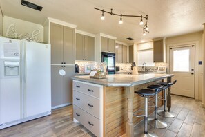 A kitchen with a central island, bar stools, a refrigerator, and a built-in oven. - Ranch Getaway With Pool and Horse Stall Access! (Calera)