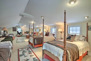 Ein geräumiges Schlafzimmer mit vier Himmelbetten, einem großen Fenster und einer gemütlichen Leseecke mit einer Lampe.
