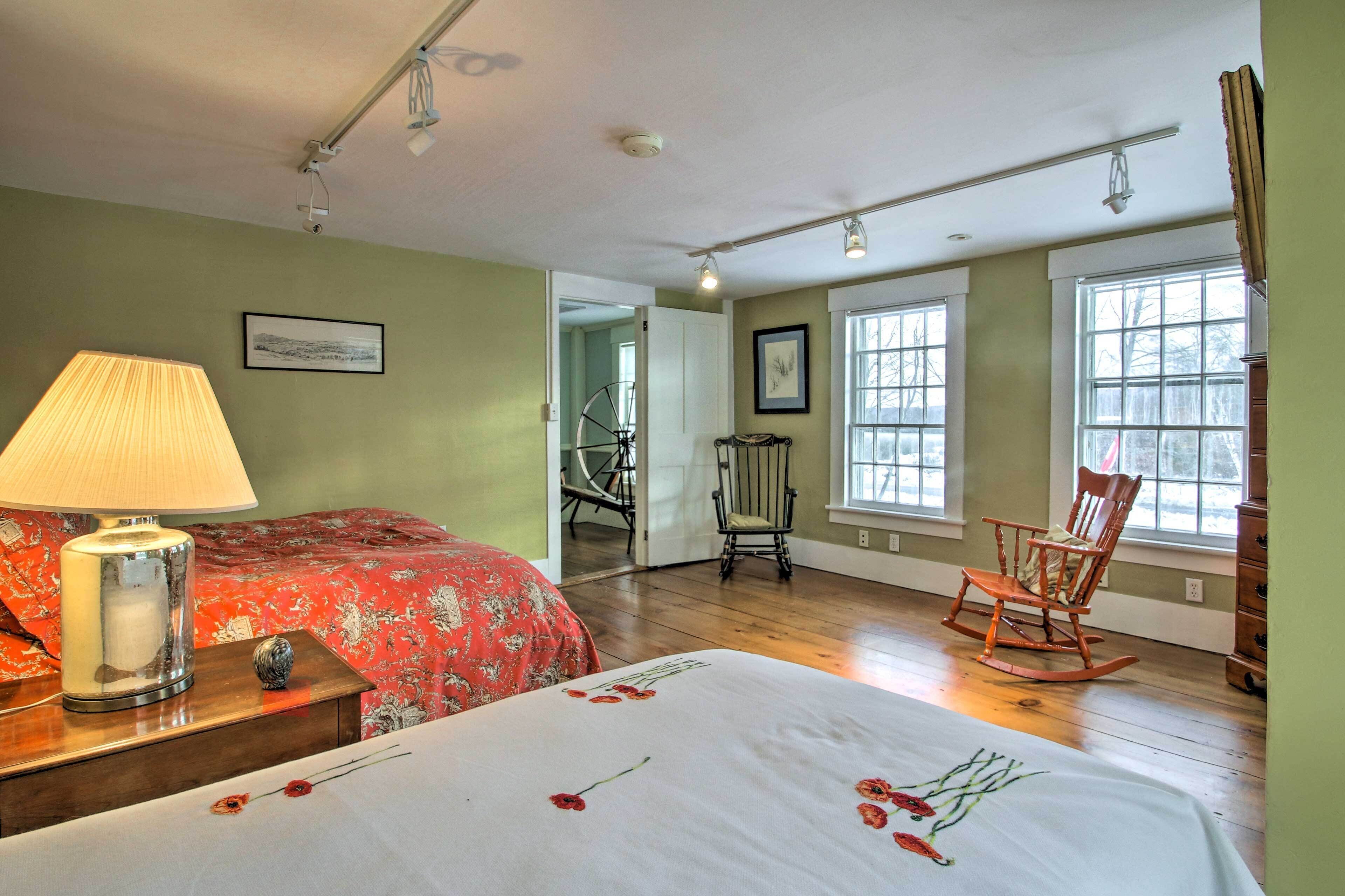 A room with a bed, a rocking chair, a lamp, and a window with a view of trees.