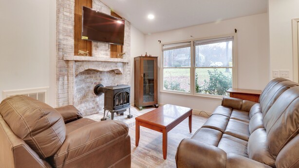 A living room with a brick fireplace, leather sofas, a wooden coffee table, and a large window with a view of greenery. - Lovely Massanutten Getaway w/ Resort Access! (McGaheysville)