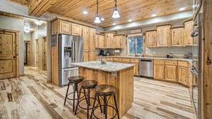 A kitchen with wooden cabinets, a central island with stools, stainless steel appliances, and a wooden ceiling. - Garden Valley Cabin w/ Loft & Large Deck! (Garden Valley)