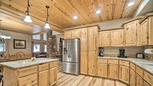 A spacious kitchen with wooden cabinets, a granite countertop, and a stone fireplace. - Garden Valley Cabin w/ Loft & Large Deck! (Garden Valley)