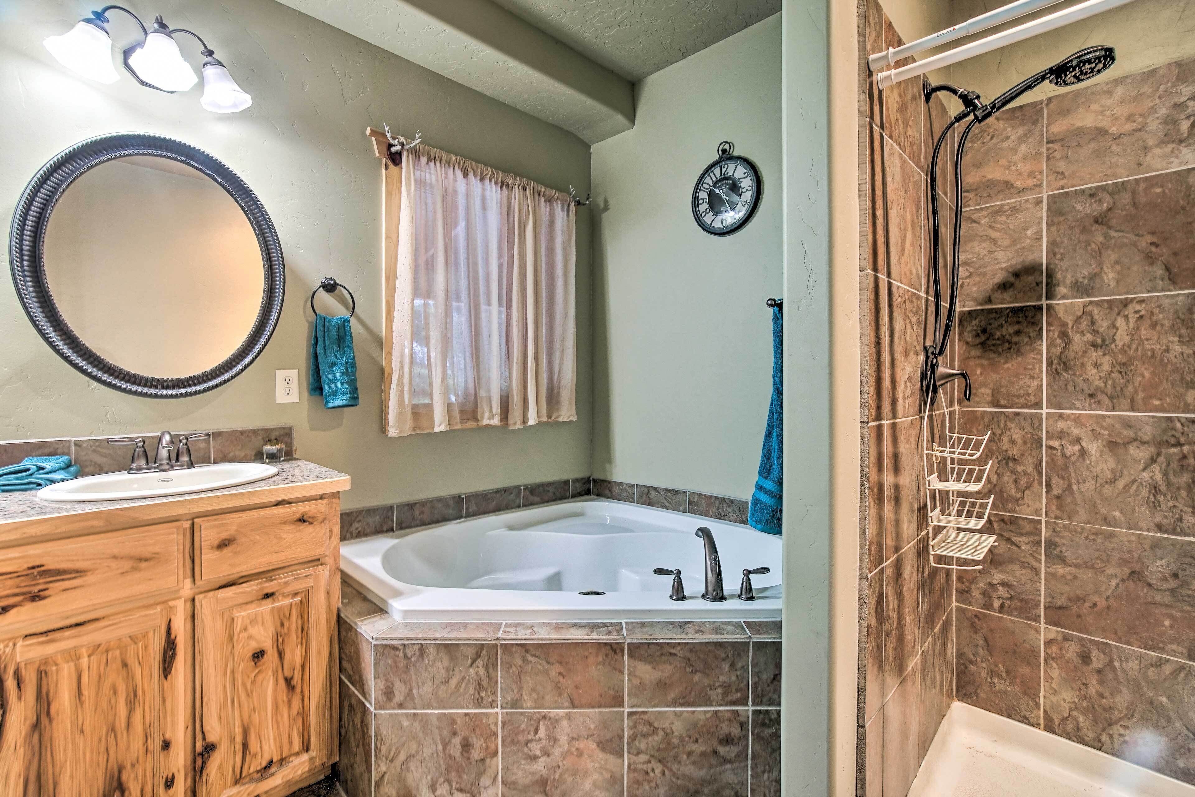 A bathroom with a wooden vanity, a large mirror, a bathtub, and a shower with a handheld showerhead.