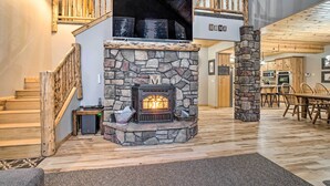 A spacious living area with a stone fireplace, wooden staircase, and a dining area. - Garden Valley Cabin w/ Loft & Large Deck! (Garden Valley)