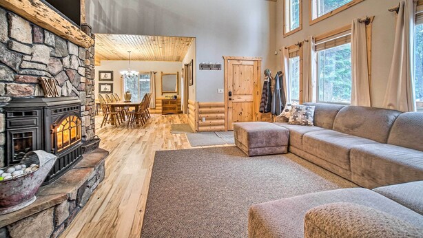 A cozy living room with a stone fireplace, a sofa, and a dining area. - Garden Valley Cabin w/ Loft & Large Deck! (Garden Valley)