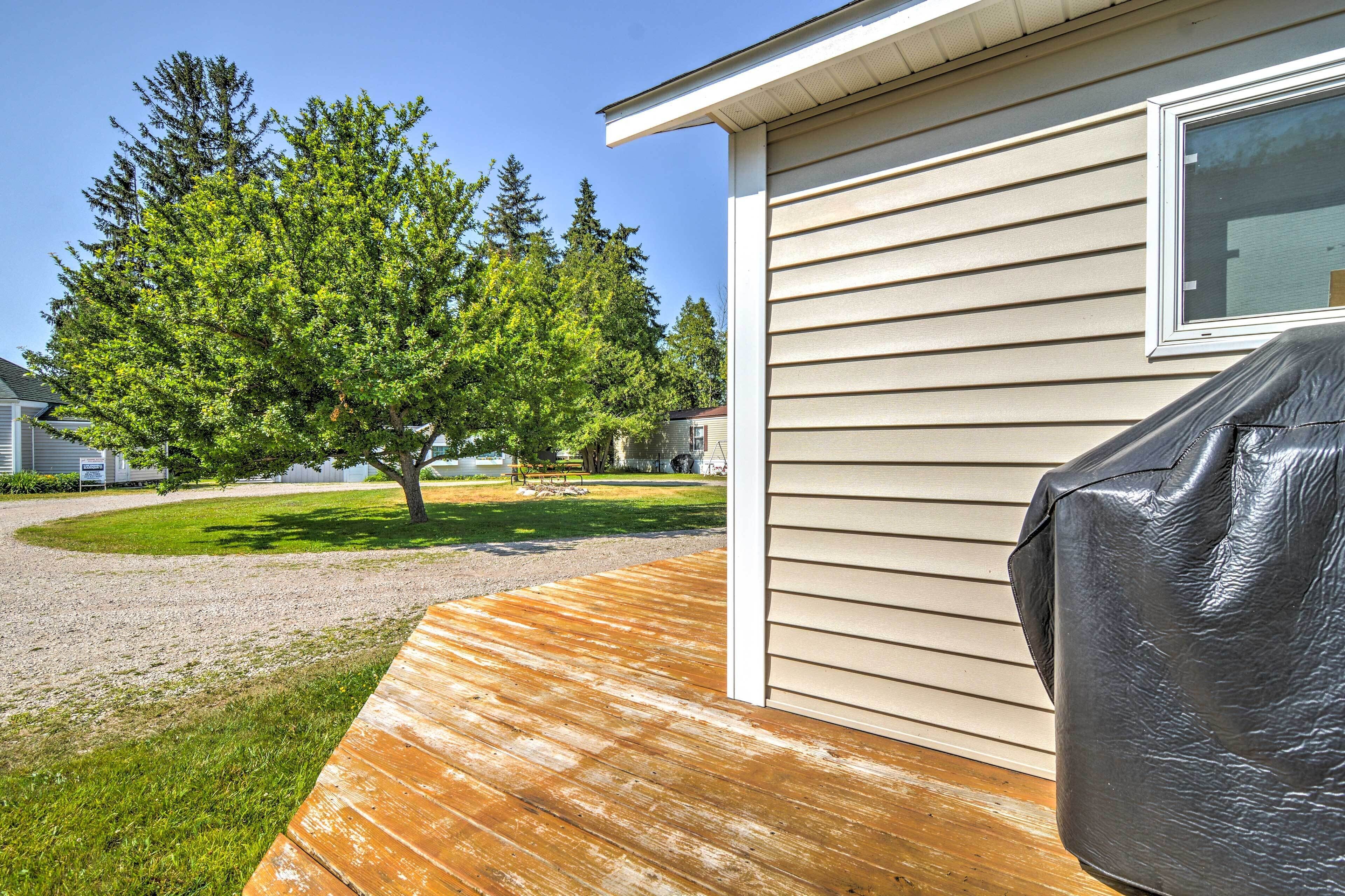 A residential property with a wooden deck, a covered barbecue area, and a house with beige siding and a window.