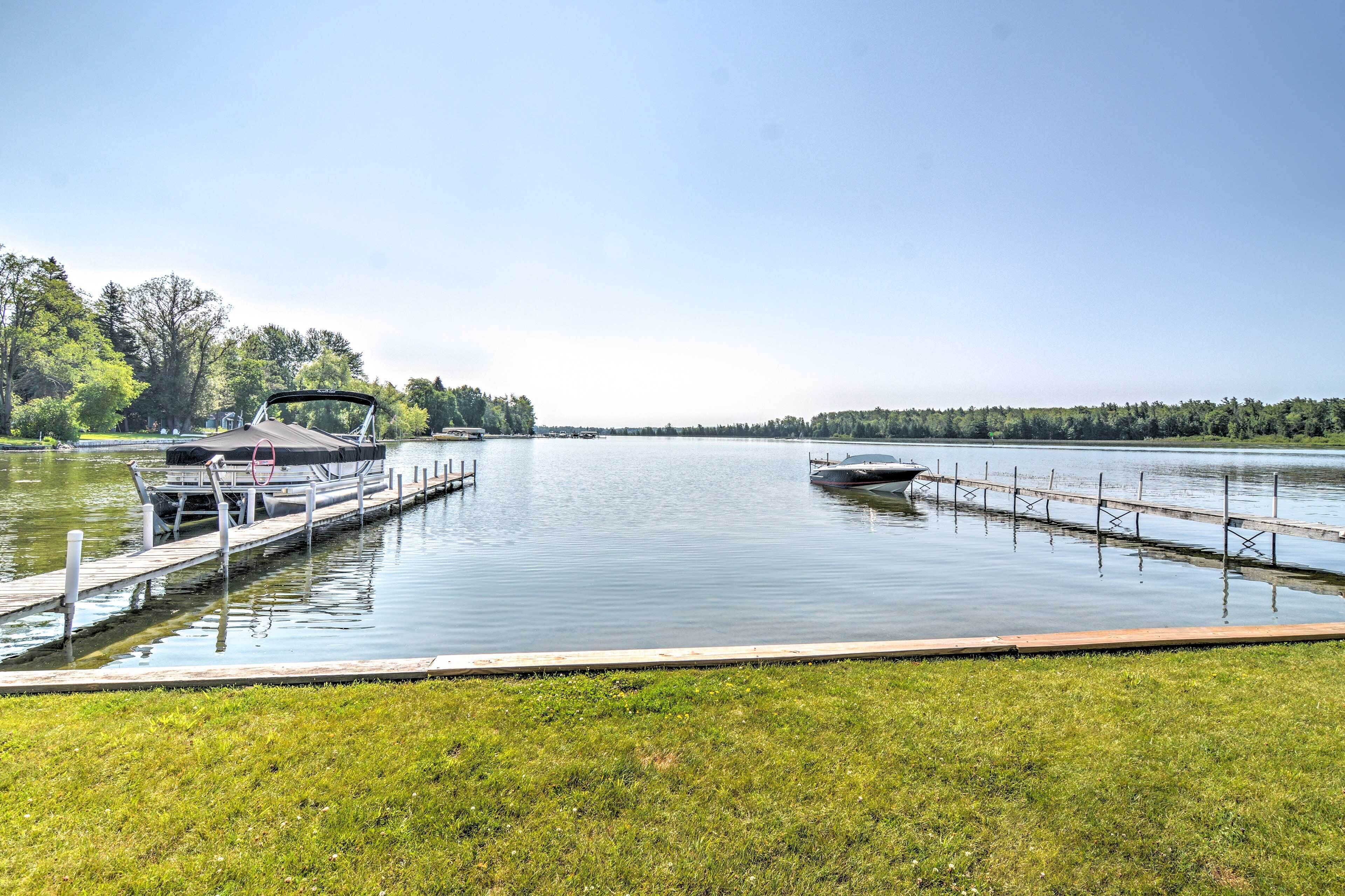 A calm lake with two boats docked at wooden piers.