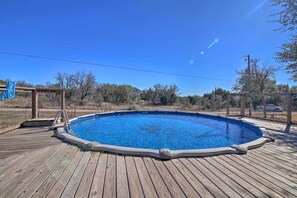 A wooden deck with a swimming pool, surrounded by a fence and trees. - Twin Acres Scenic Ranch in Texas Hill Country (Florence)