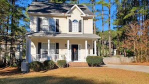 A two-story house with a front porch, a garage, and a fenced yard. - Wendell Home w/ Fenced Yard, Close to Raleigh (Wendell)