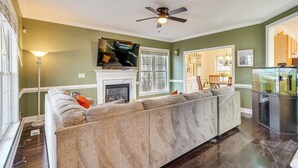 A living room with a large sectional sofa, a fireplace, a television, and a fish tank. - Wendell Home w/ Fenced Yard, Close to Raleigh (Wendell)