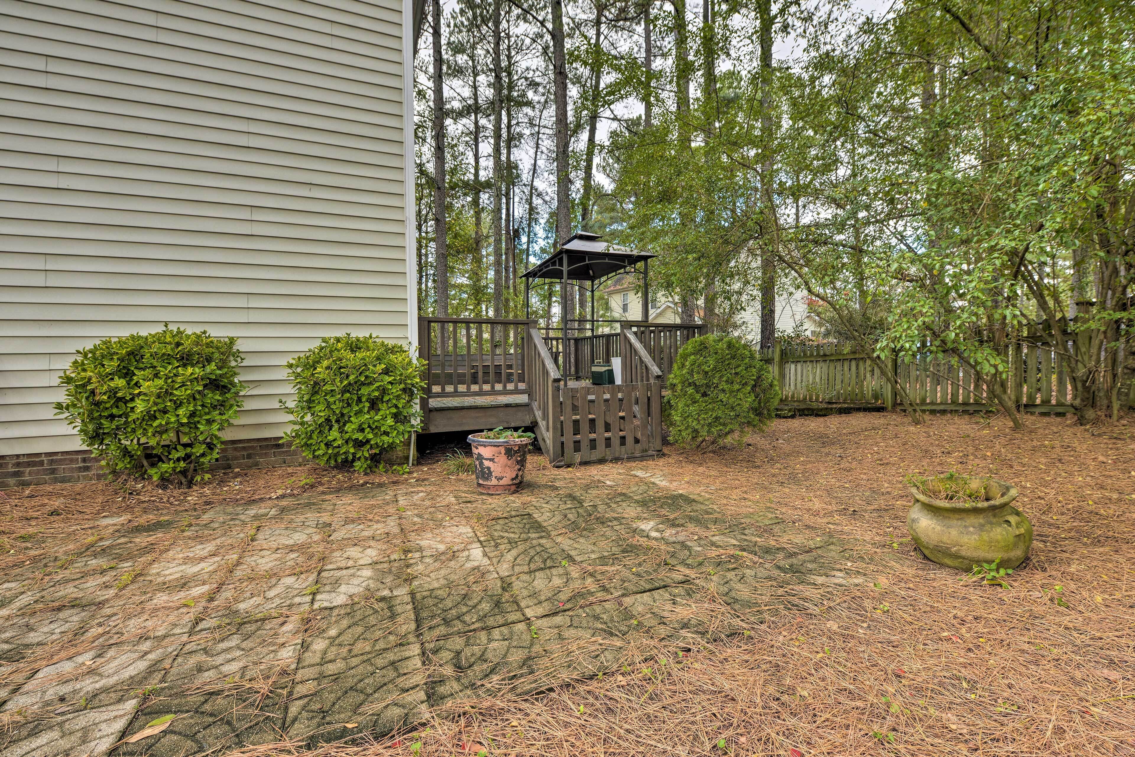 A wooden deck with a gazebo, surrounded by a wooden fence and dense trees.