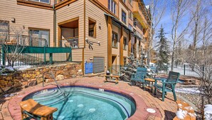 A pool area with a hot tub, wooden deck, and outdoor seating.