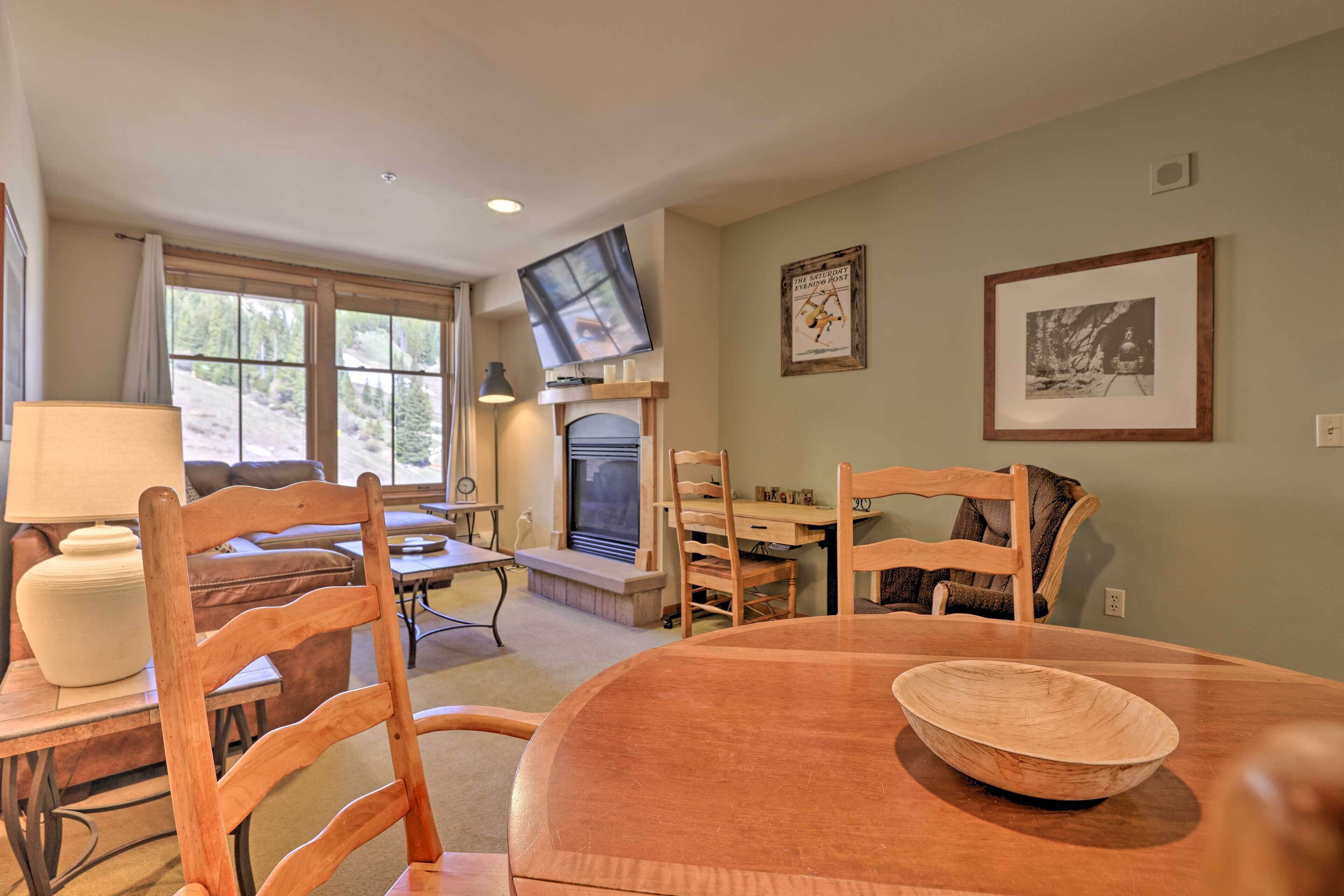 A cozy living room with a fireplace, wooden furniture, and artwork on the walls.