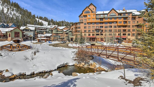 A snow-covered resort with a central building, a small stream, and surrounding lodges.