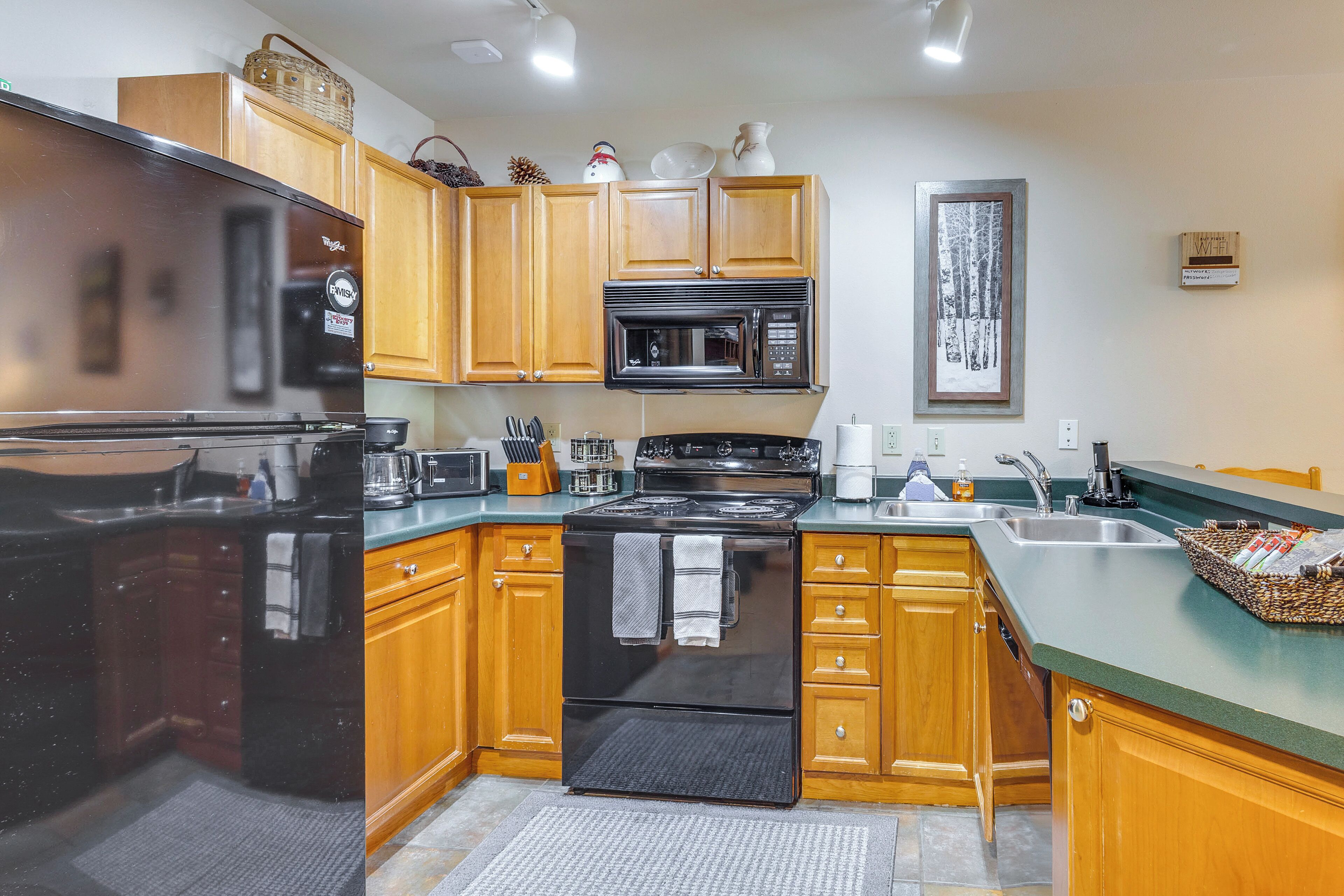 A kitchen with wooden cabinets, a black refrigerator, a microwave, and a stove.