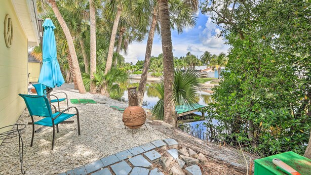 A patio with a blue umbrella, a rustic vase, and a chair. - Remodeled Siesta Key Studio Near Beach! (Siesta Key)