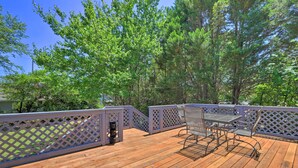 A wooden deck with a metal table and chairs, surrounded by a lattice fence. - Spacious Lanett Haven w/ Sunroom + Large Deck (Lanett)