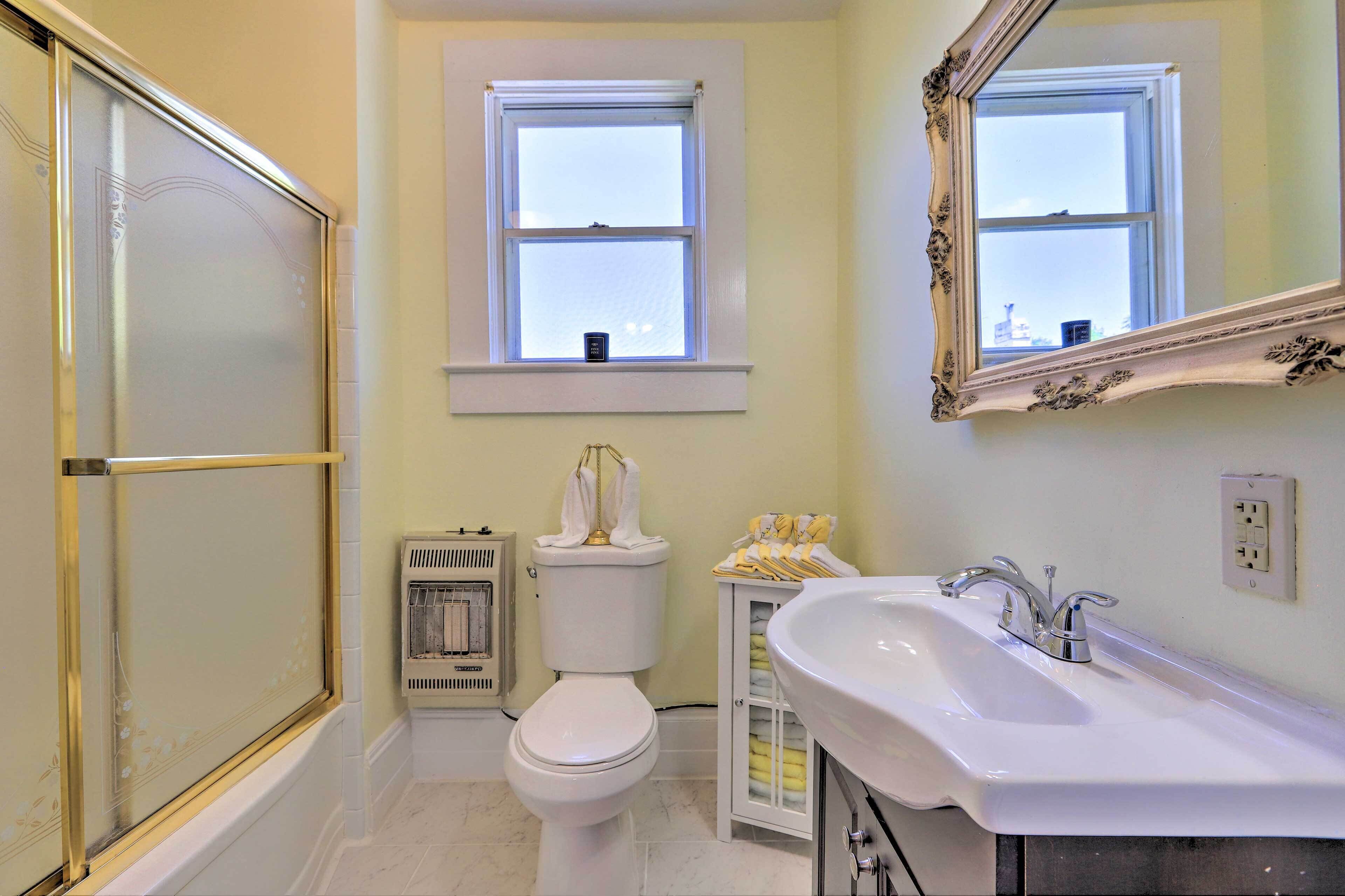 A bathroom with a bathtub, toilet, sink, and a window above the toilet.