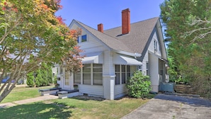 A single-story house with a front porch, a chimney, and a small front yard. - Spacious Lanett Haven w/ Sunroom + Large Deck (Lanett)