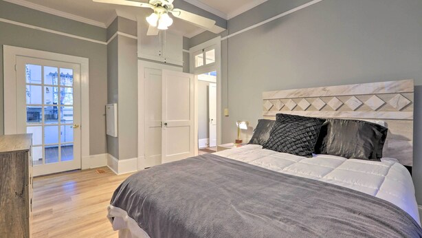 A bedroom with a bed, a ceiling fan, a door, and a view through a window. - Spacious Lanett Haven w/ Sunroom + Large Deck (Lanett)
