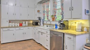 A kitchen with white cabinets, a granite countertop, a dishwasher, and a microwave. - Spacious Lanett Haven w/ Sunroom + Large Deck (Lanett)