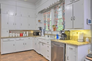 A kitchen with white cabinets, a granite countertop, a dishwasher, and a microwave.
