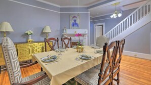 A dining room with a table set for four, chairs, a chandelier, and a staircase in the background. - Spacious Lanett Haven w/ Sunroom + Large Deck (Lanett)