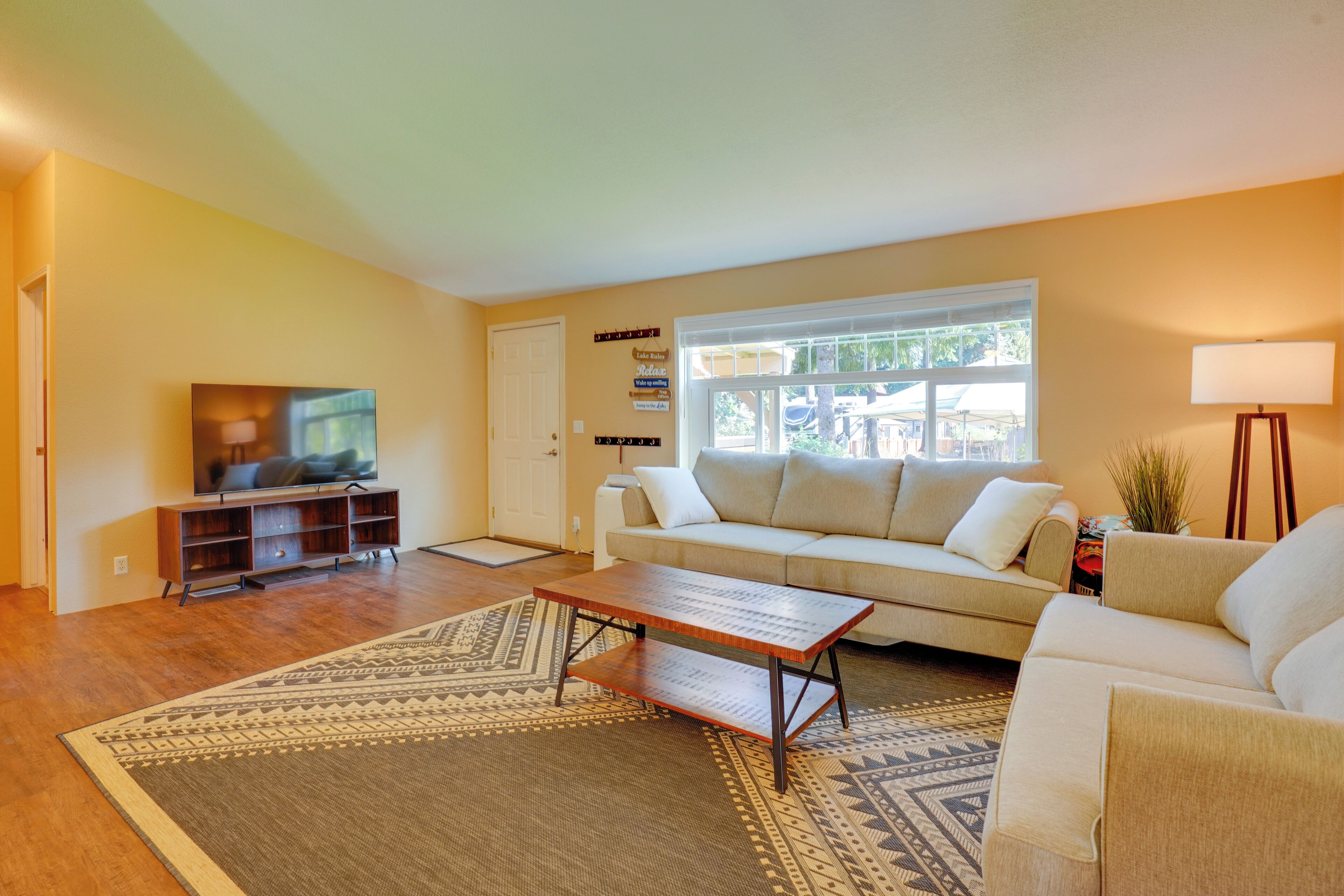 A living room with a sofa, a coffee table, a TV, and a window with blinds.